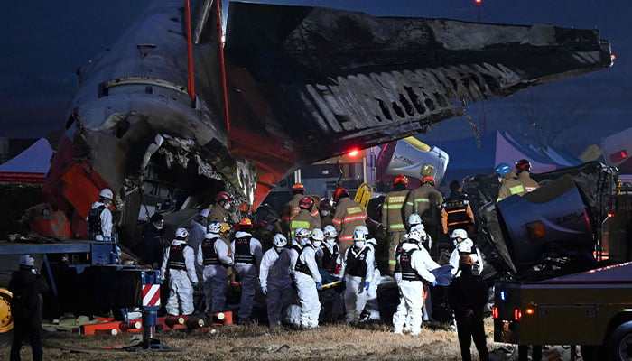 Firefighters and rescue personnel carry the body of a victim near the site where a Jeju Air Boeing 737-800 series plane crashed and burst into flames at Muan International Airport, South Jeolla Province, the December 29, 2024. — AFP