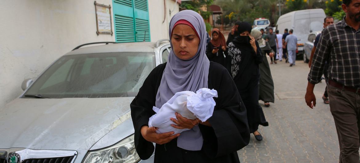 A woman carries the body of a newborn killed in an attack on the Nasser Hospital in Khan Younis, Gaza.