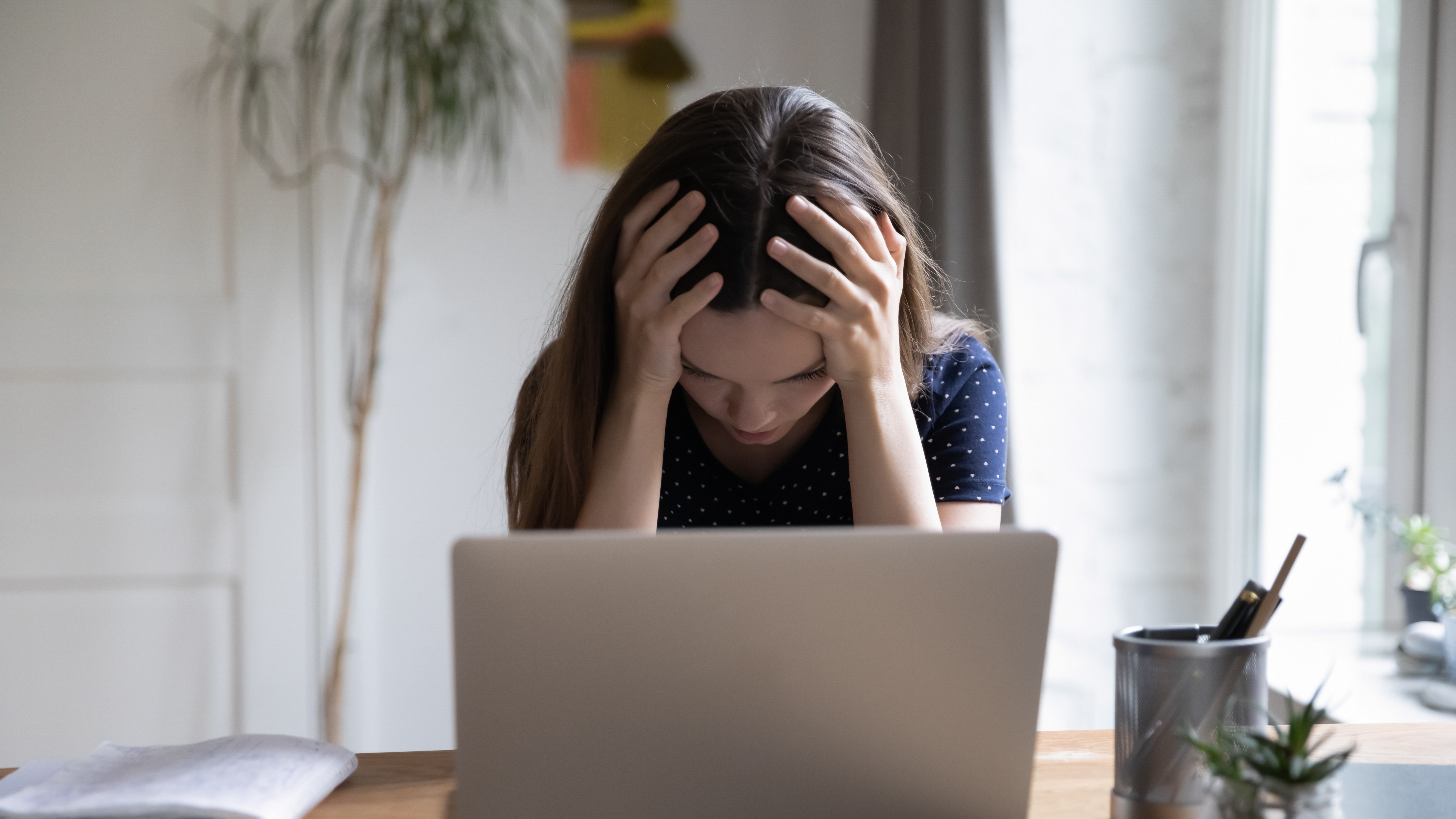 The frustrated laptop user touching the head on the work table with the computer