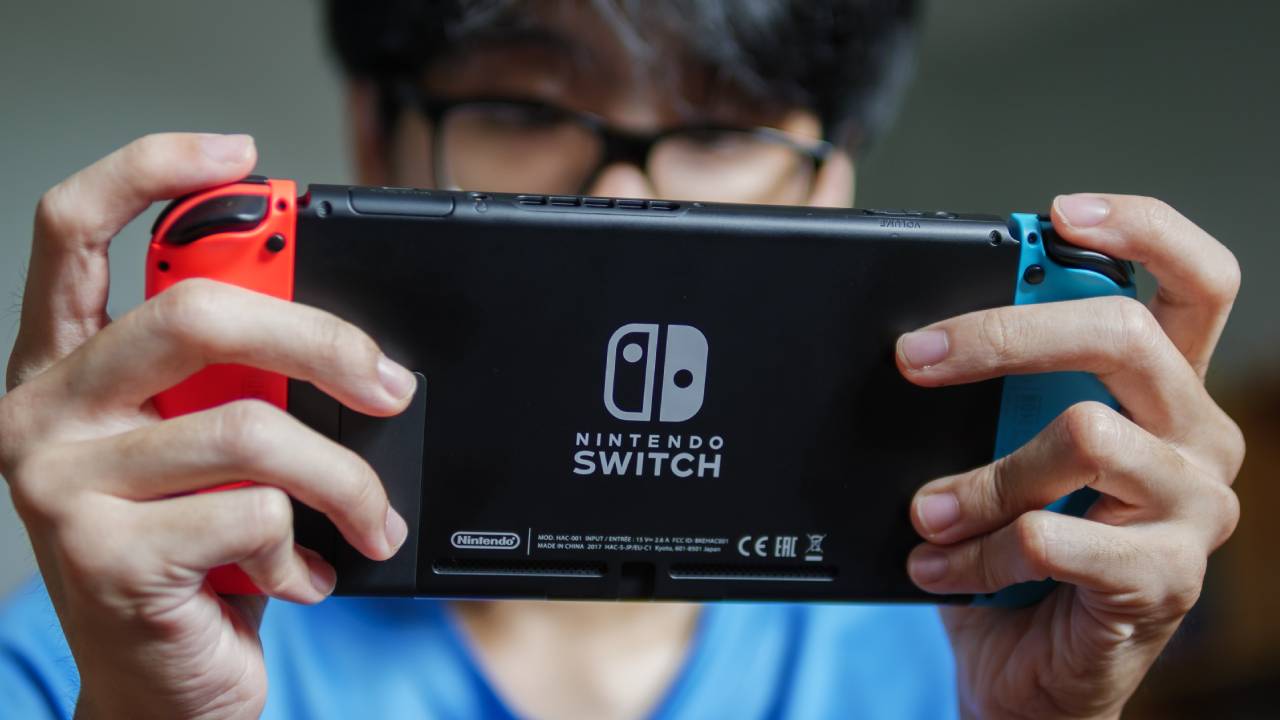 A person looking down playing with Nintendo Switch.