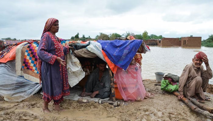 A family takes refuge in a higher field after rains and floods during the Monzón season in Dera Allah Yar, Jafferab District, Baluchistan on August 25, 2022