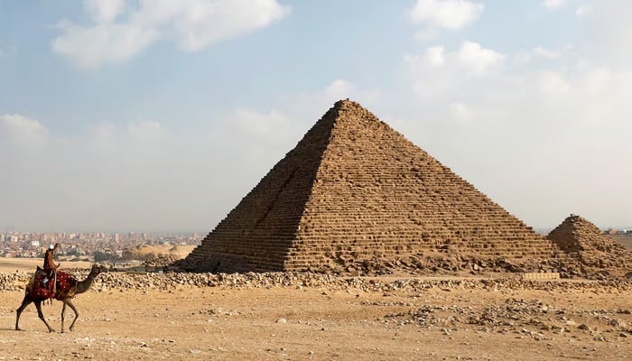 A camel guide awaits customers next to the Khafre or Chefren pyramid on the Pyramid Plateau of Giza in Giza, Egypt, December 18, 2020. - Reuters