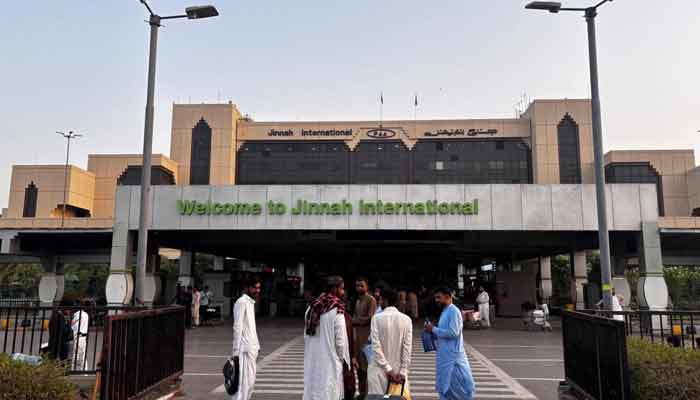 Passengers wait outside at Jinnah International Airport after all national and international flights were canceled in Karachi, Pakistan, on May 7, 2025. - AFP