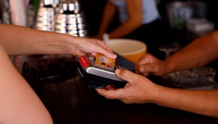 This representation image shows a woman who pays with a credit card in a restaurant in Playa del Inglés, Maspalomas on the island of Gran Canaria, Spain, May 3, 2022. - Reuters