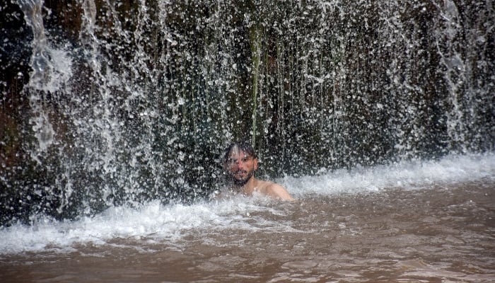 A young man cools in Angori's waterfall during high temperature in Islamabad on May 15, 2025. - Online