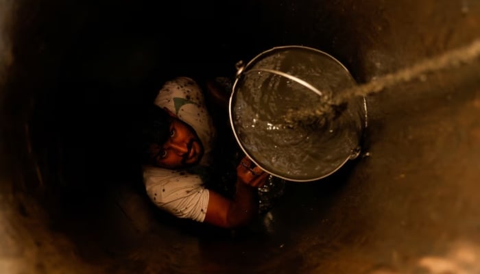 A man cleans a small well in Chandrapur, India, February 3, 2025. - Reuters