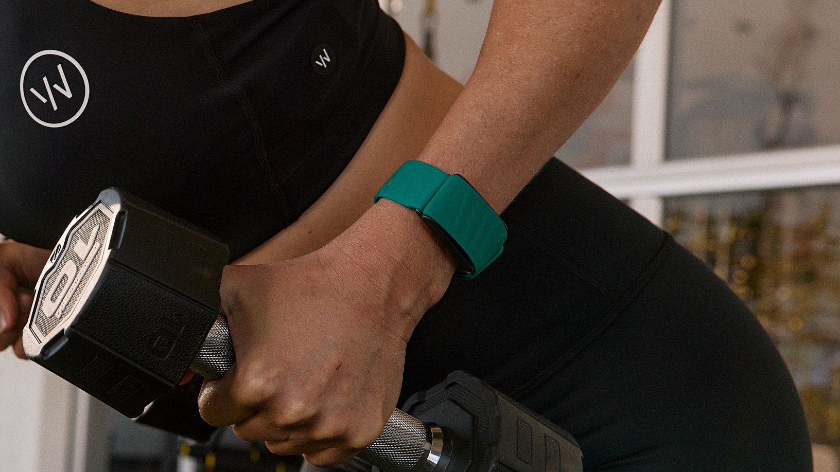 Woman raising the dumbbell while wears the Whoop device on the wrist