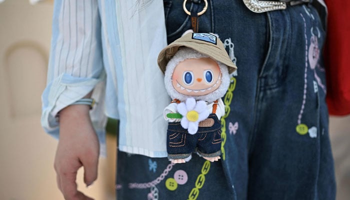 A woman with a Labubu character figure while watching the land of the Pop Mart in Beijing, China on June 18, 2025. - AFP