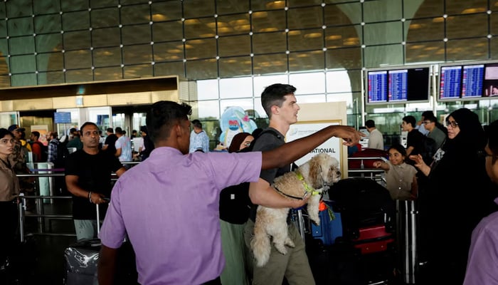 A volunteer guides passengers to their respective doors after several airlines had flight delays after an important technical problem hit the registration systems for airlines, at the Chhatrapati Shivaji Maharaj International Airport in Mumbai, India, July 19, 2024.