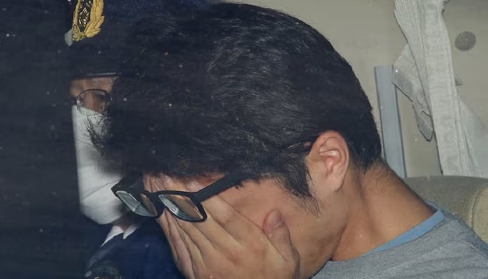 Takahiro Shiraishi covers his face inside a police car in Tokyo, in this photo taken by Kyodo in November 2017 and thrown by Kyodo on December 15, 2020. - Reuters