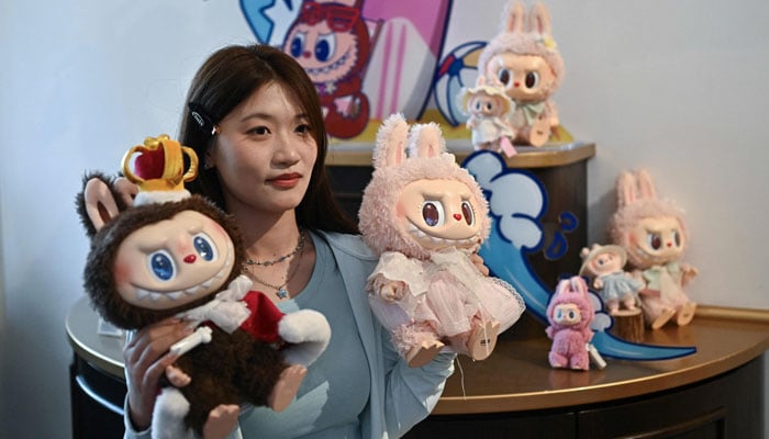 A woman poses with characters from Labubu (L) and Mokoko in an exhibition hall while visiting Pop Mart Park Land in Beijing, China on June 18, 2025. - AFP