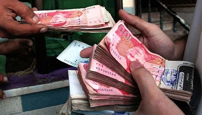 You can see two people holding notes from the Pakistani currency rupee in their hands. - AFP/file