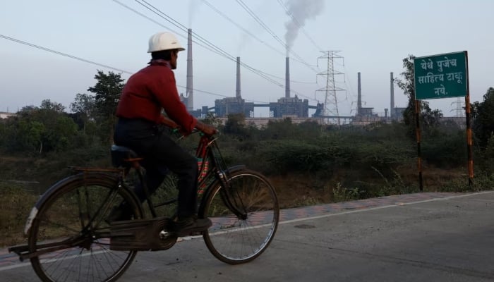 A factory worker rides a bicycle beyond the super thermal energy plant in Chandrapur, India, February 3, 2025. - Reuters