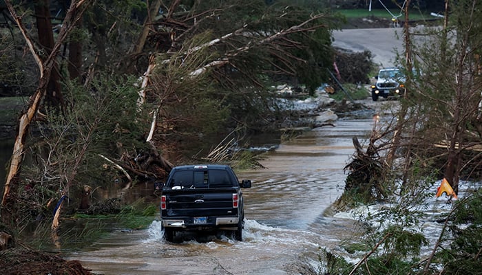A vehicle rides along a flooded road, after sudden floods, in Hunt, Texas, USA July 6, 2025. - Reuters