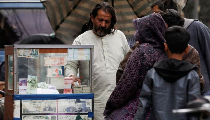 A currency corridor is located near its stand, which is decorated with images of currency notes, while it comes to customers, along a road in Karachi on January 27, 2023. - Reuters