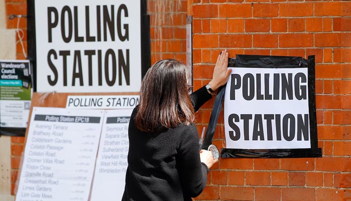 A woman attached a sign on the wall of an electoral table during the local elections in London, Great Britain, on May 5, 2022. - Reuters