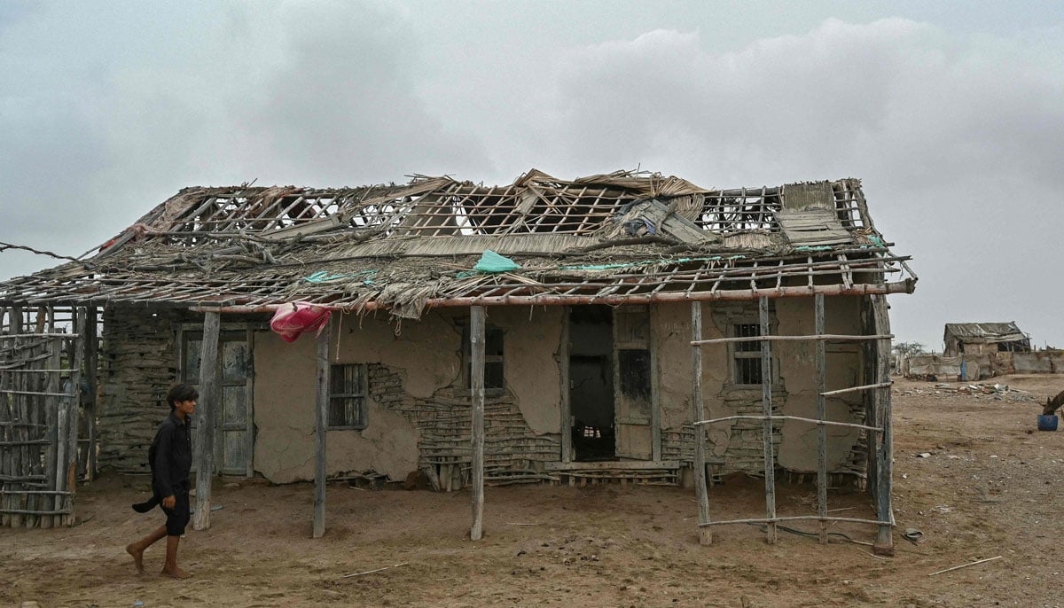 A child passes through an abandoned house in one of the villages of the city of Kharo Chan, in the Delta del Indo on June 25, 2025. - AFP