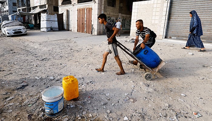 A child pulls a container in a cart while the Palestinians wait to collect water amid scarcity in the middle of scarcity, in the city of Gaza on August 6, 2025. - Reuters