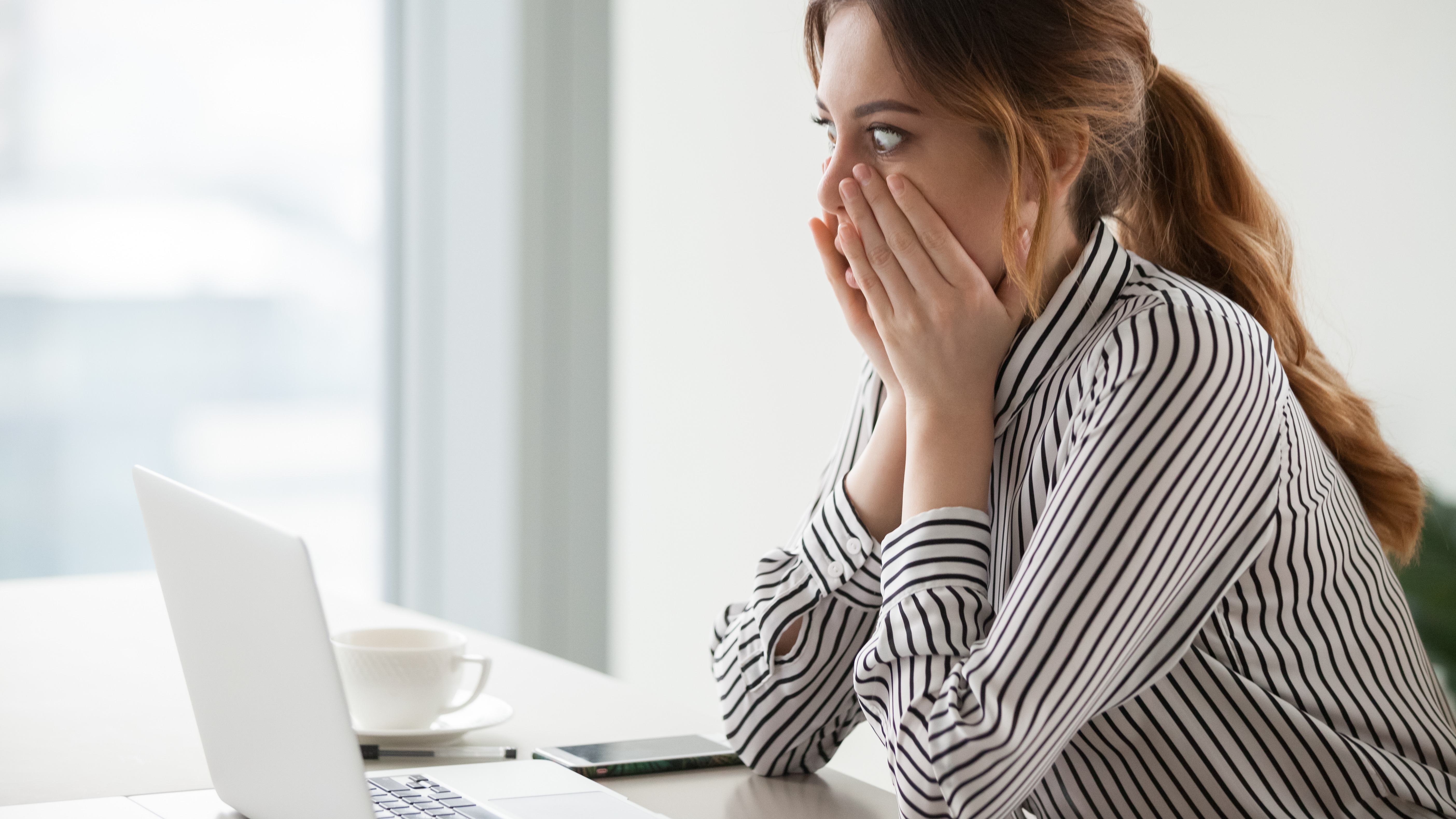 Surprised female worker looking at laptop screen