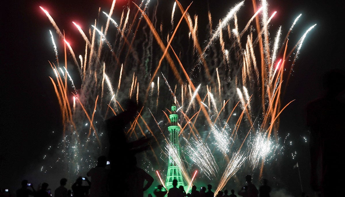 People look at artificial fires exploiting on the illuminated monument of mine-e-pakistan during the celebration of Independence Day in Lahore on August 14, 2025.-Reuters