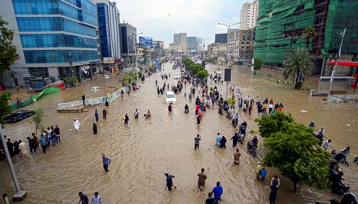People walk on a flooded path after the monzonic rain in Karachi on August 19, 2025. - Reuters