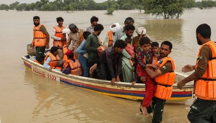 Rescue workers help evacuate the people affected by the floods of their houses affected by floods after heavy monsoon rains in the Punjab Rajanpur district. - AFP/file