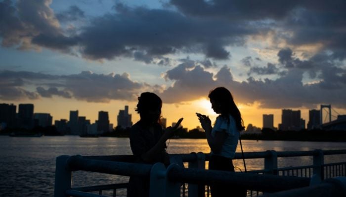 Two women who use their smartphones in Japan. - AFP