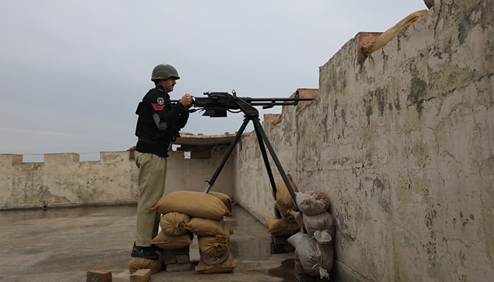 A police officer with an infantry machine gun of 12.7 mm takes position on the roof of the Sarband Police Station, on the outskirts of Peshawar, Pakistan, February 9, 2023. - Reuters
