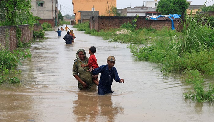 Residents are going through a flooded street, after the monsors of the monsoon and the increase in water levels in Punjabs Sialkot on August 27, 2025. - Reuters
