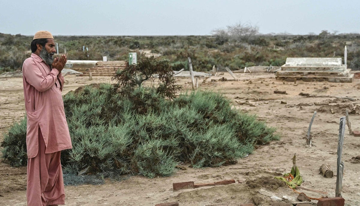 Habibullah Khatti, a local resident, pray before the tomb of their mothers before leaving the village of Abdullah Mirbahar in the city of Kharo Chan, in the Delta del Indo on June 25, 2025. - AFP