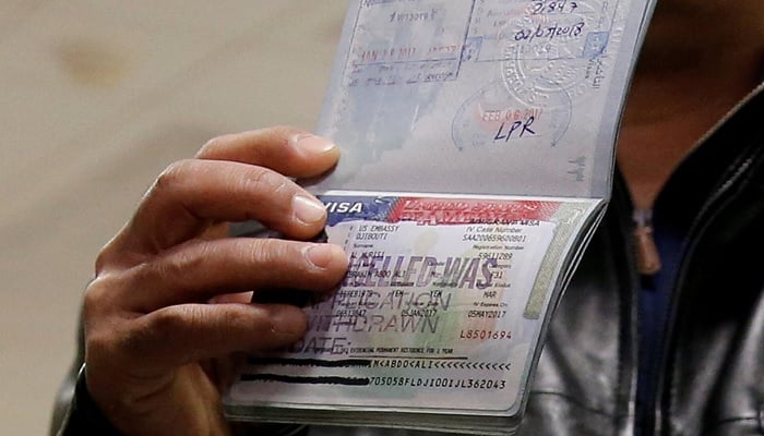 A traveler shows the visa canceled in his passport to journalists at Washington Dulles International Airport in Chantilly, Virginia, USA, February 6, 2017.