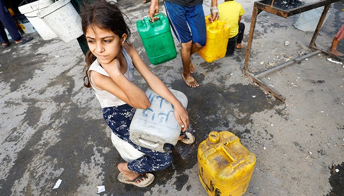 A Palestinian girl waits with containers to collect water in the middle of scarcity, in the city of Gaza on August 6, 2025. - Reuters