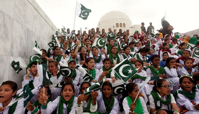 Children at school greet the national flag and sing patriotic songs in a ceremony to celebrate Independence Day in the mausoleum of Muhammad Ali Jinnah in Karachi. - Reuters