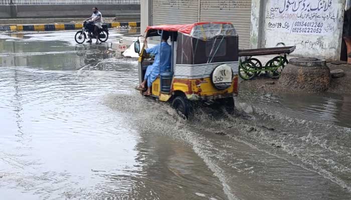 A Rickshaw goes through a road flooded in Karachi after heavy rains on August 19, 2025. - PakGazette.TV