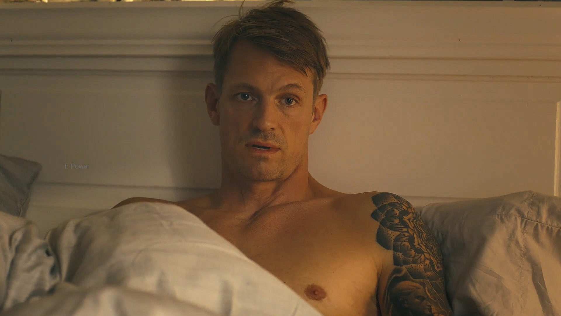 A rick flag in topless jr sitting on a bed in Peacemaker season 2 episode 3