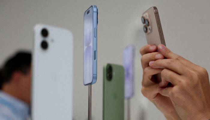 A person uses a phone to capture iPhones on display during the apple event at the Steve Jobs Theater in Cupertino, California, USA., September 9, 2025. - Reuters