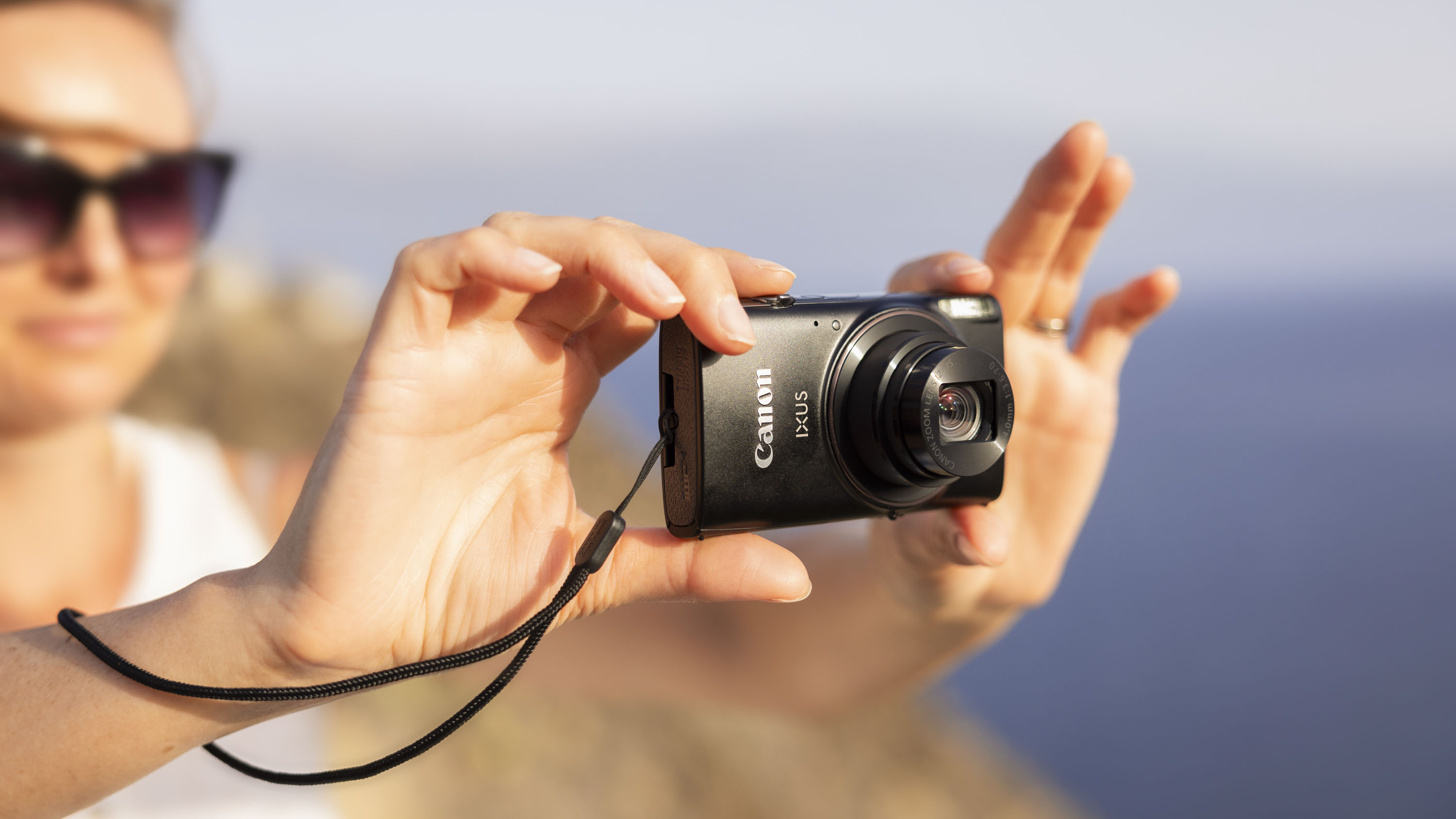 Canon Powershot Ixus 285 Hs A Point and Shoot Camera in the hands of women, outdoors sunny