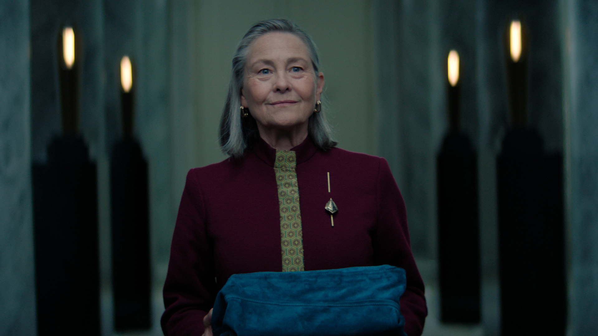 Ambassador Quent holding a fabric covered object at the season 3 Episode 10 Foundation