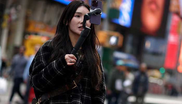 A woman makes a video with a mobile phone to publish on Tiktok while standing at Times Square in New York City, New York, USA, March 13, 2024. - Reuters