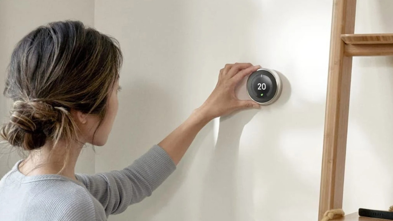 The learning thermostat nest mounted on a wall controlled by a woman