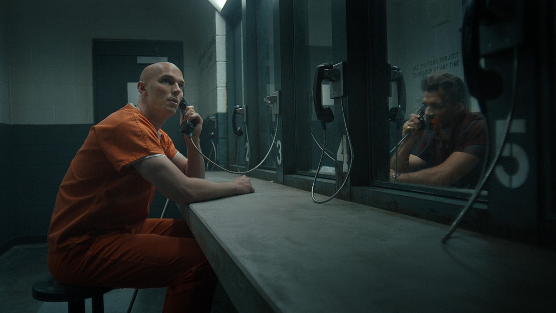 Lex Luthor Looking around while talking to Rick Flag SR through a prison phone in Peacemaker Season 2 Episode 6