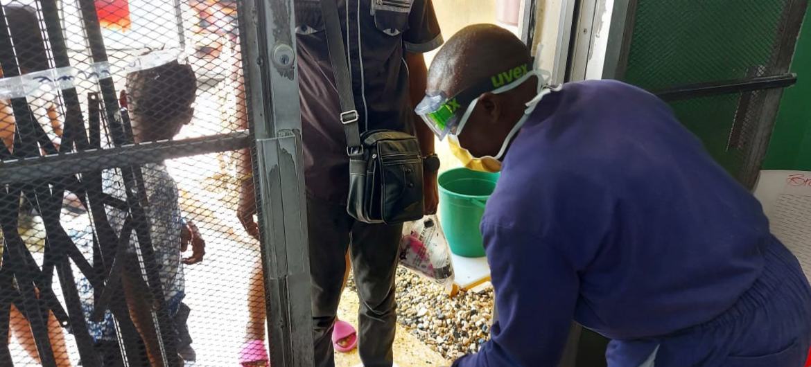 A health worker carries out sanitation procedures as people enter a cholera installation in Haiti.