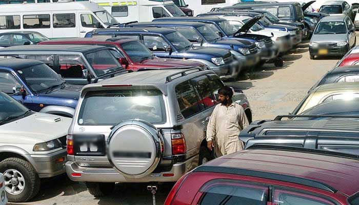 An employee of a car exposure room walks in the middle of new cars that are exhibited in a Karachi car distributors center. - AFP/file
