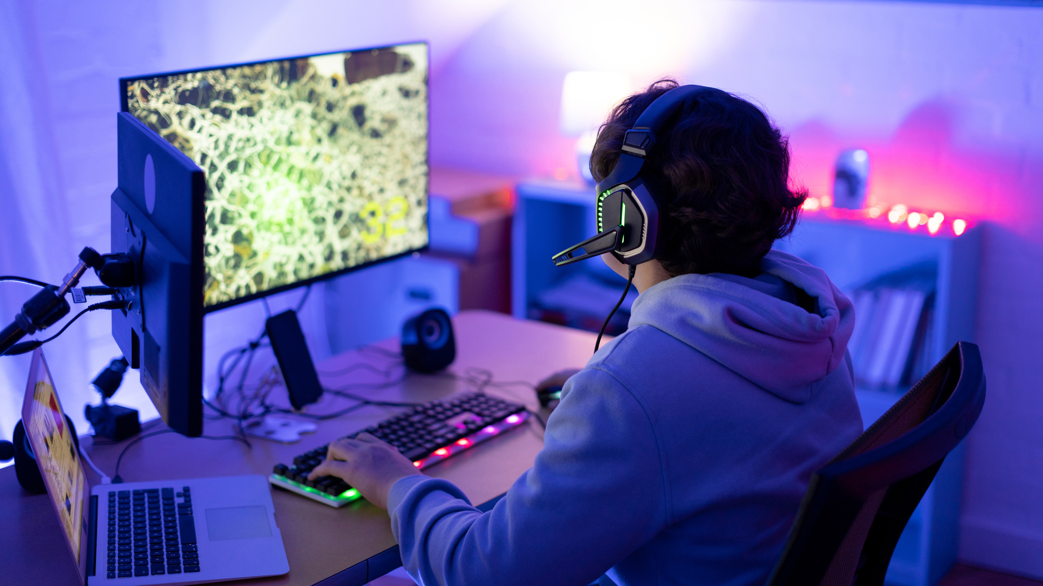 Teenager playing on a PC for games with two monitors
