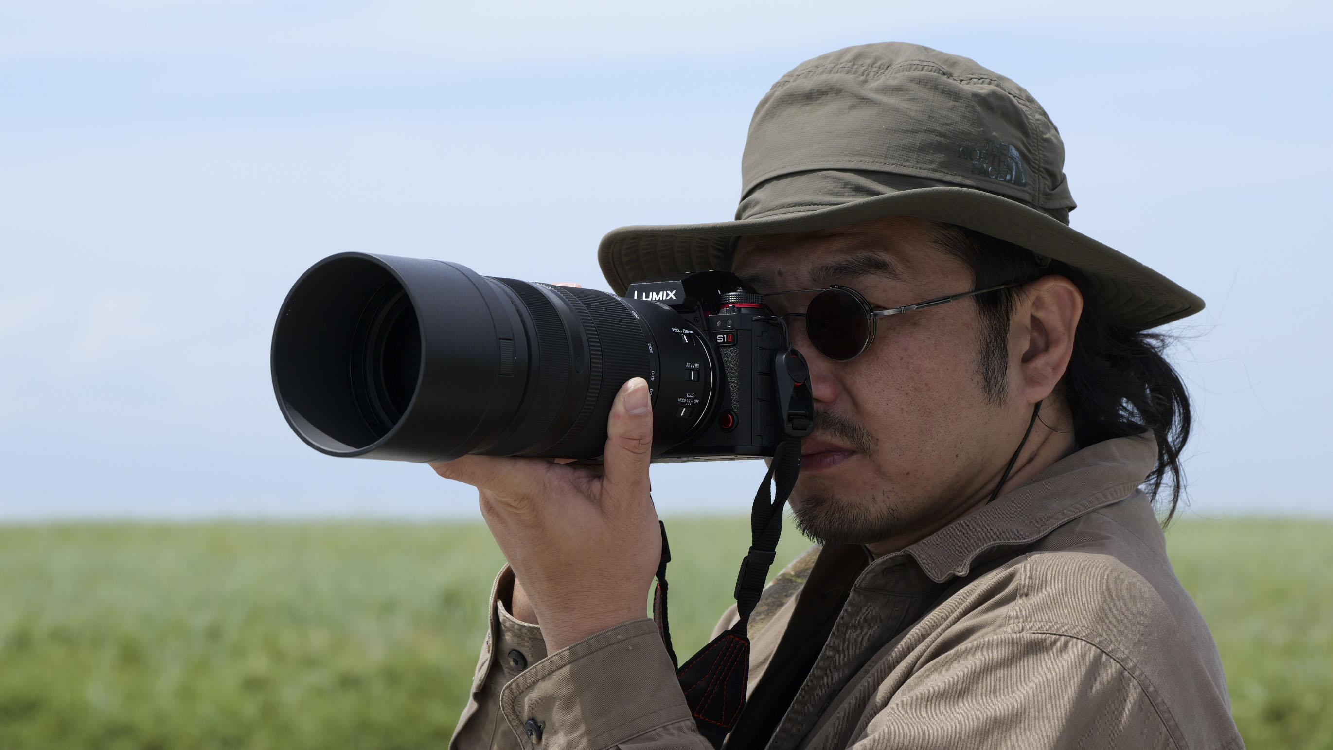 PANASONIC LUMIX S 100-500 mm F5-7.1 LENS OR AUBJECT TO A LUMIX S1 II WITH Photographer taking the camera to his eye