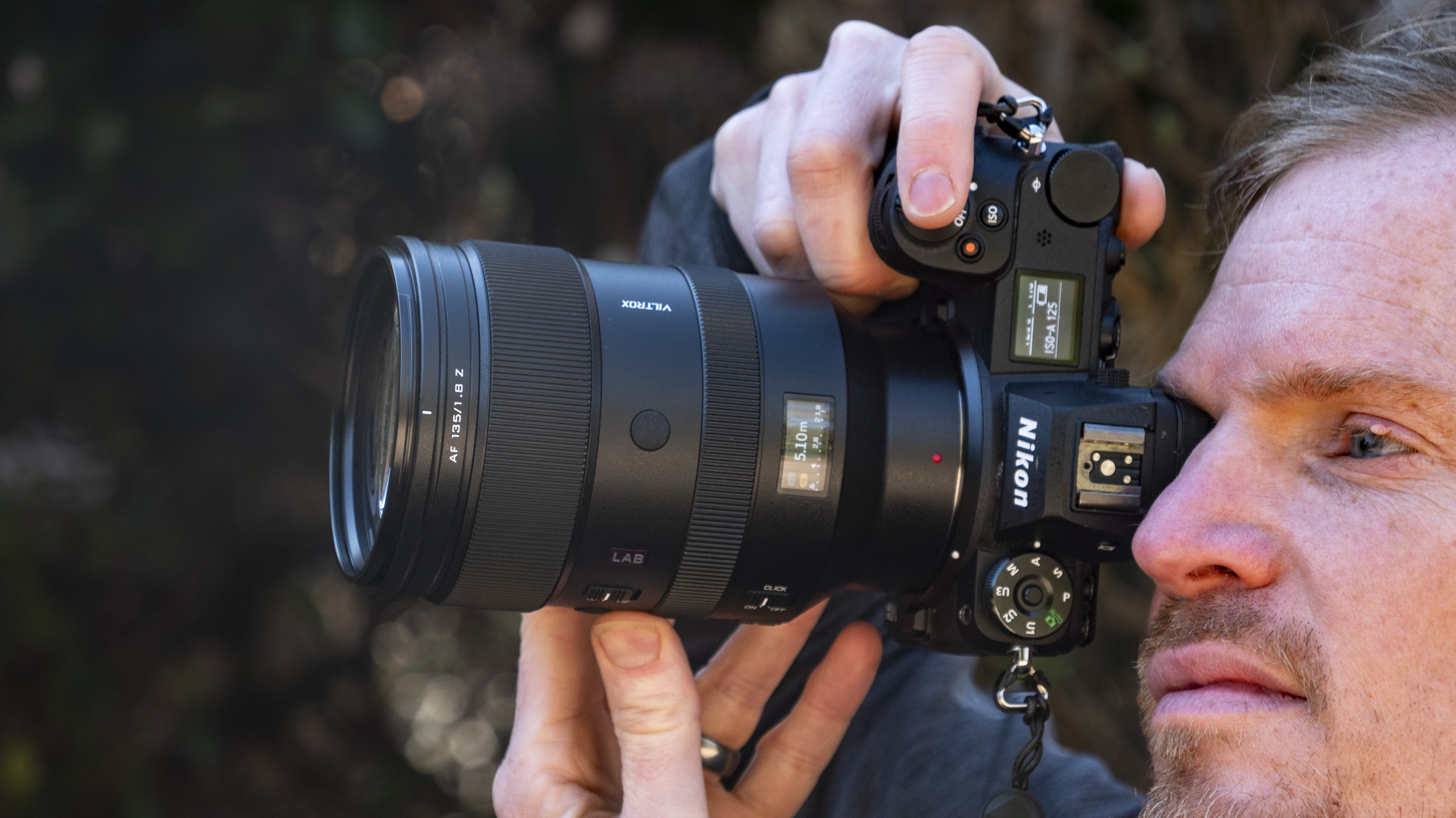 Laboratory lens Viltrox 135 mm F1.8 for Nikon Z-Mount, in hand, together with a Nikon Z6 II