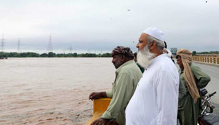 Men stand on a bridge over the Chenab River, after the rains of the monsoon and the increase in water level in Wazirabad, in Punjab on August 27, 2025. - Reuters