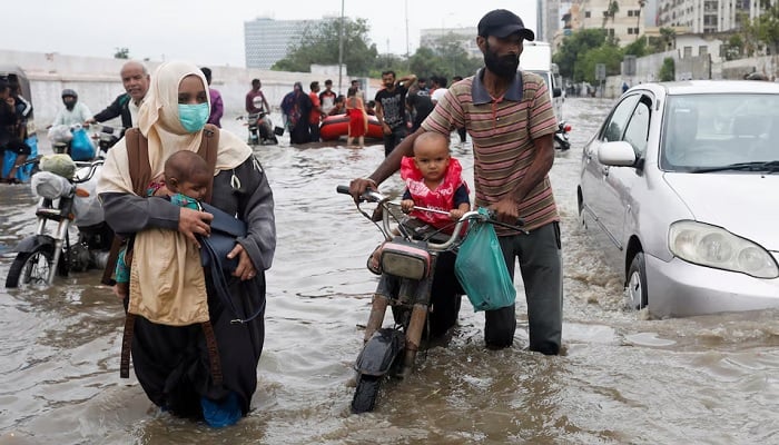 A family is going through a flooded road during the Monzón season in Karachi. —Reuters/file