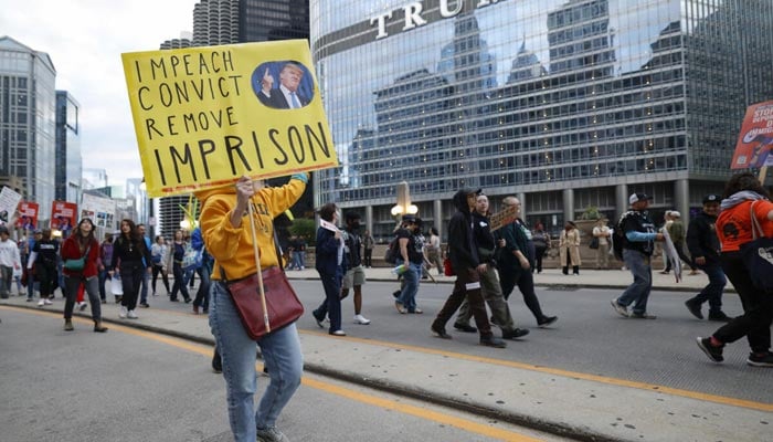 People have anti-triunfo signs while Trump International & Tower in Chicago passes during a demonstration against the planned deployment of National Guard troops on September 6, 2025.-AFP