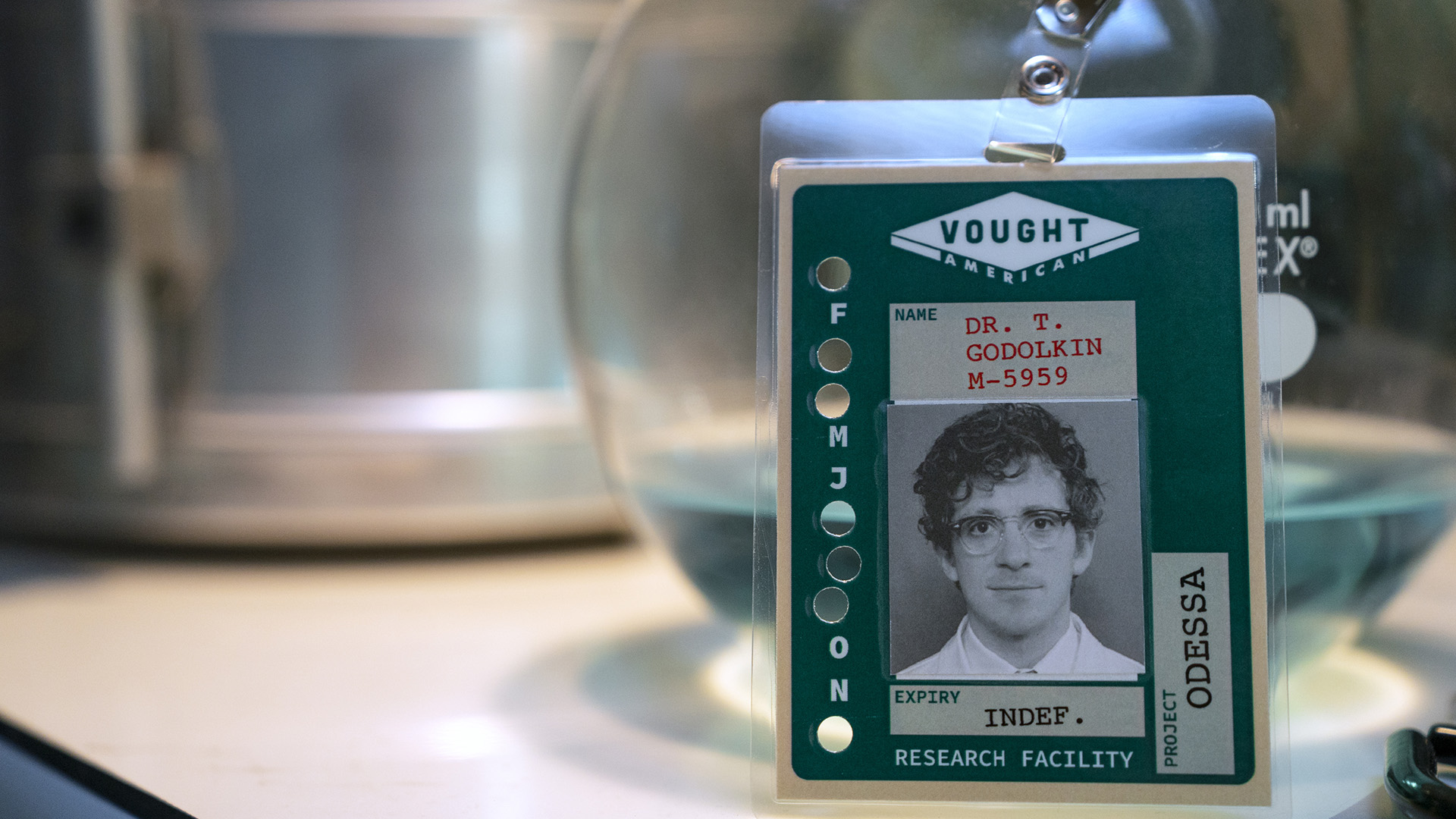 A screen capture of Nametag's badge by Dr. Thomas Godolkin supported on a table in season 2 of generation V